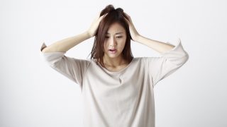 頭を抱えて困っている女性の画像